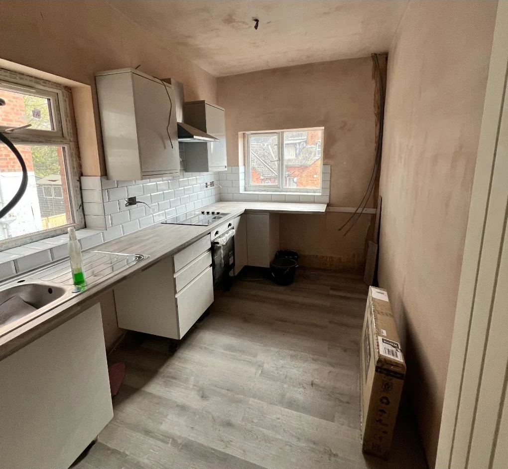 Kitchen units being installed against freshly plastered walls